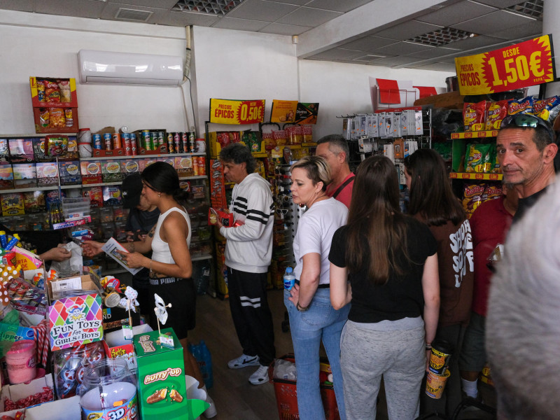Vecinos de Elche compran en una tienda de ultramarinos durante el apagón eléctrico que se ha producido hoy lunes en la Península Ibérica