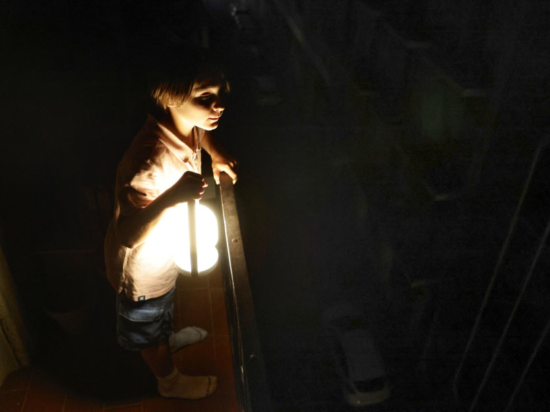 Un niño con una lampara mirá desde el balcón la calle todavía a oscuras esta madrugada en el centro de Barcelona durante el corte de suministro eléctrico que afecta este lunes a España y que ha dejado sin servicio el metro y el tranvía de Barcelona y todas las líneas de ferrocarril, y sin red de teléfonos móviles ni internet