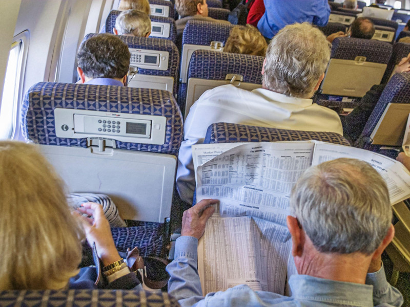 Pasajeros leen el periódico durante un vuelo de avión