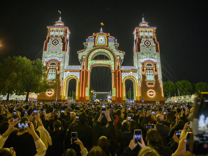 La Feria de Abril de Sevilla, la de la vuelta a la fiesta de una semana de duración ya está en marcha oficialmente, tras encenderse el alumbrado, como siempre, a las 12.00 de la noche en punto, al mismo tiempo en su impresionante portada que en las 15 calles de su Real