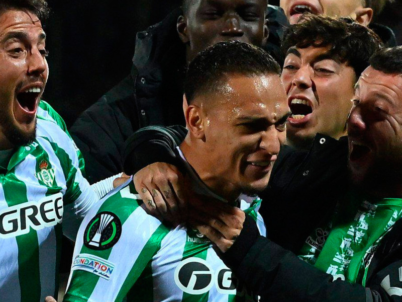 Antony, con gesto emocionado, recibe el abrazo de sus compañeros para celebrar el pase del Betis a la final de la Conference