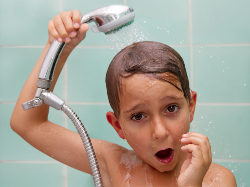 Un niño con el mango de la ducha