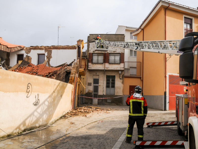 Los bomberos subidos a una grúa de bomberos en la calle trabajan en un edificio derrumbado