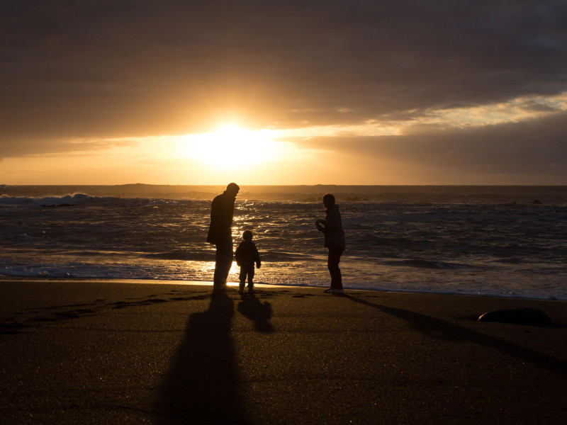 Silueta de familia feliz en la playa mirando la puesta de sol en el océano