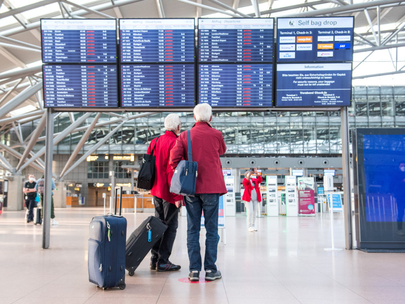 Pasajeros mirando un marcador del aeropuerto