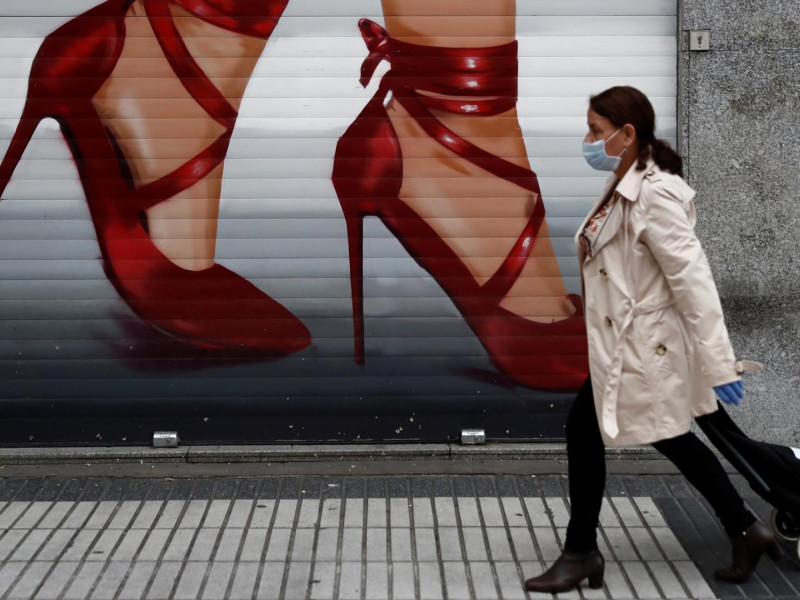 Una mujer camina delante de un negocio cerrado durante la pandemia del coronavirus