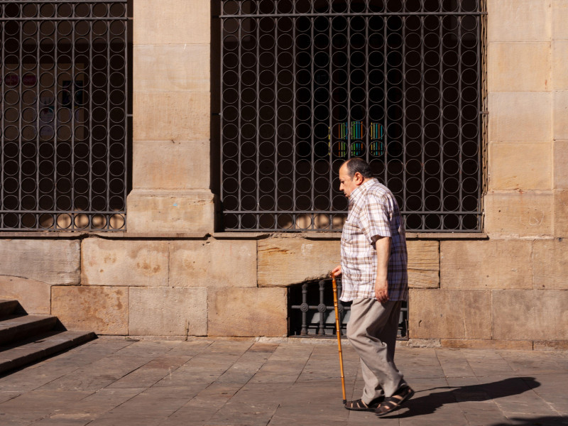 Anciano caminando por la calle de Pamplona con bastón