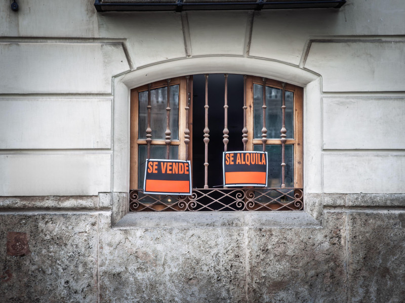Rótulos de inmobiliaria ('se vende', 'se alquila', en español) en una ventana de Valencia