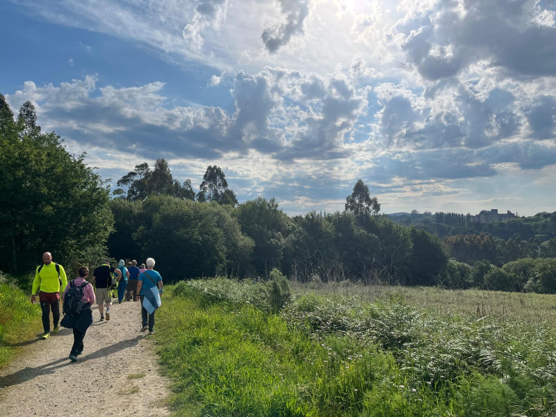 Un grupo de turistas camina por la ruta de Vite con la ciudad de Santiago al fondo