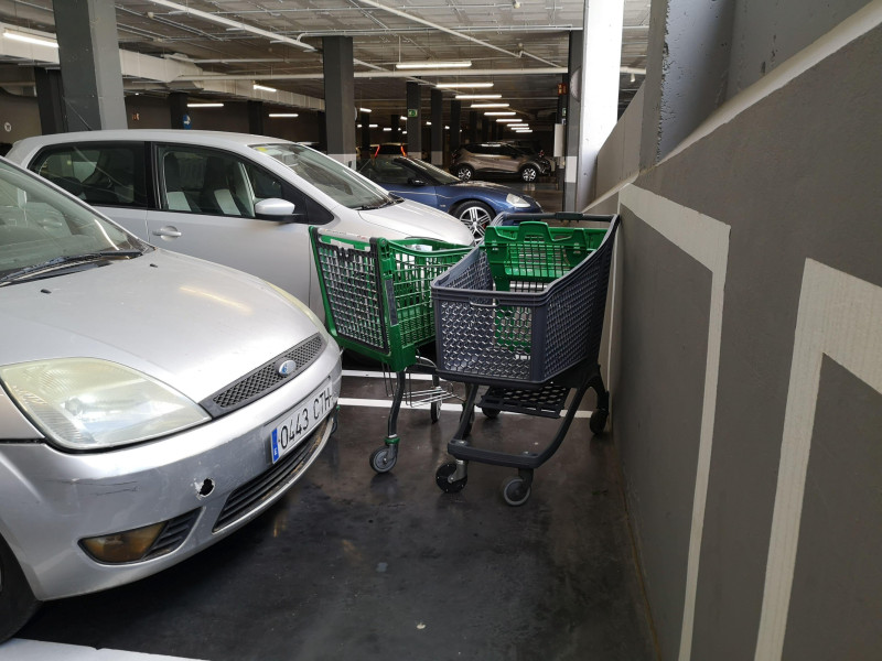Carritos de compra abandonados entre los coches en el aparcamiento del supermercado.