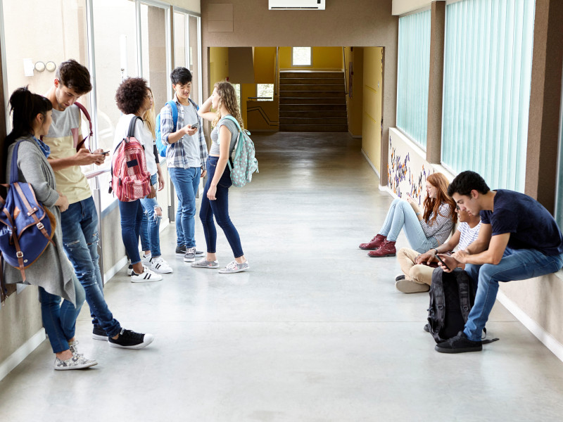 Un grupo de estudiantes comunicándose a través de sus teléfonos móviles entre clase y clase