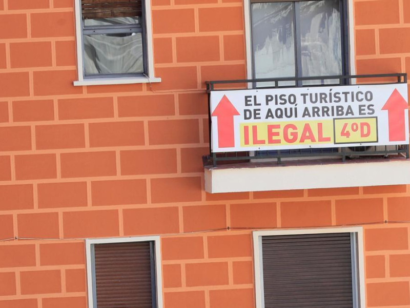 Cartel que avisa de la ilegalidad del piso turístico de un vecino