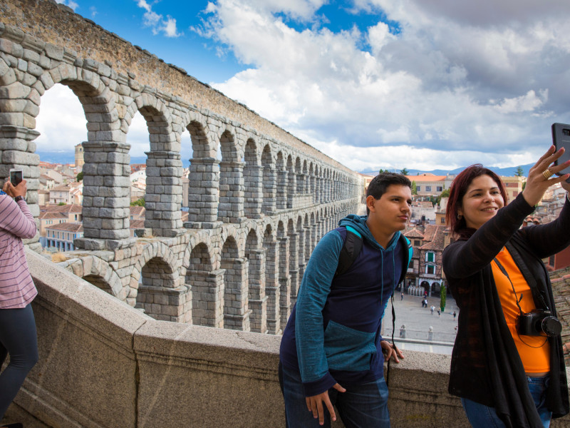 Dos turistas haciéndose un selfie al lado del acueducto de Segovia