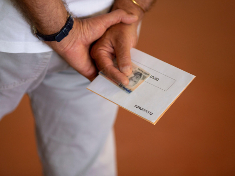 Un hombre sostiene su DNI antes de votar
