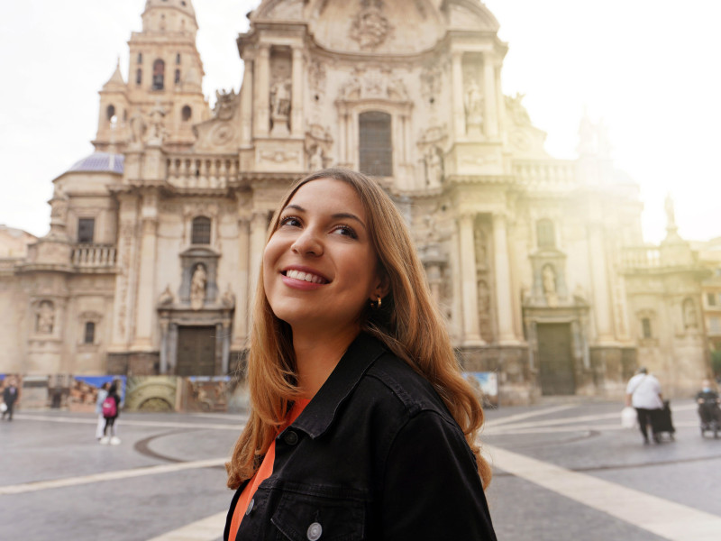 Chica turista visitando Murcia con la Iglesia Catedral de Santa María al fondo