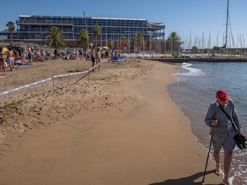 Se ve a un anciano caminando por la playa, desafiando el cierre de la playa al público decretado por la Guardia Urbana para evitar la presencia de manifestantes en el agua.