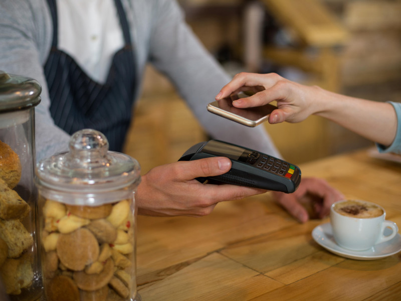 Una mujer pagando con su teléfono móvil en una cafetería gracias al modo NFC