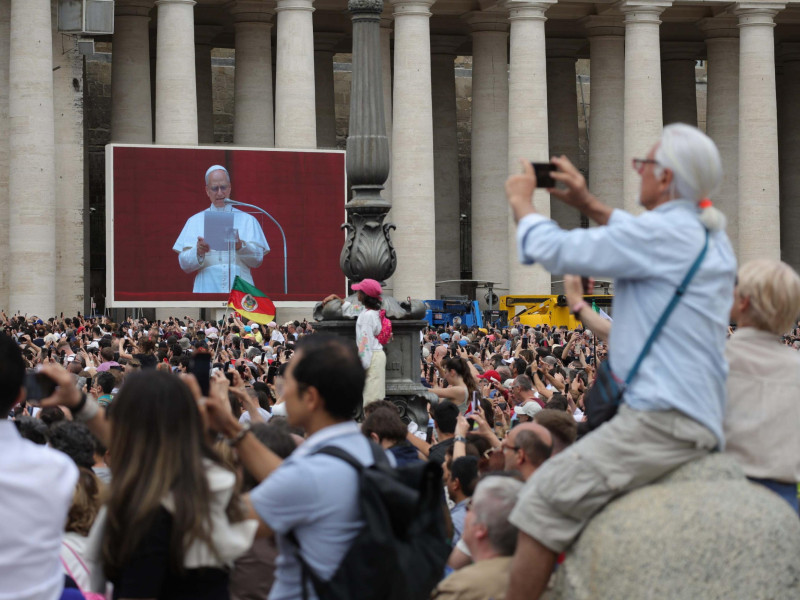 Pope Leo XIV is displayed on a large screen as he leads the Regina Caeli prayer from the central loggia of Saint Peter's Basilica in Vatican City