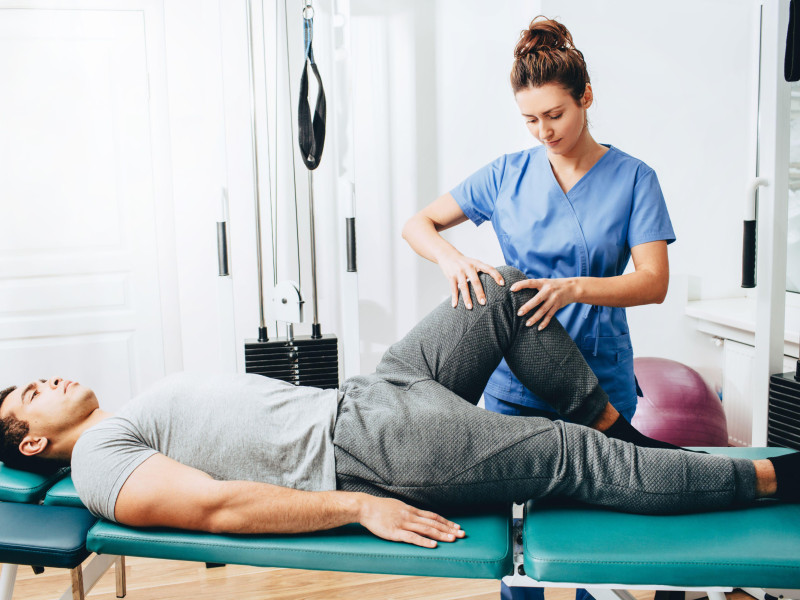 Fisioterapeuta examina la rodilla del paciente.