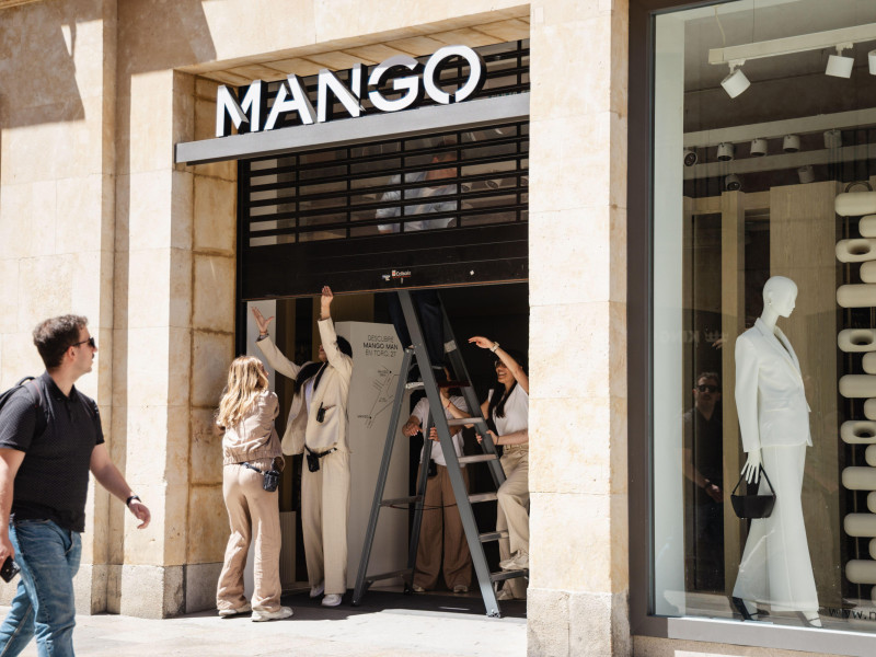 Varios empleados cierran manualmente la persiana de la tienda de Mango en Salamanca