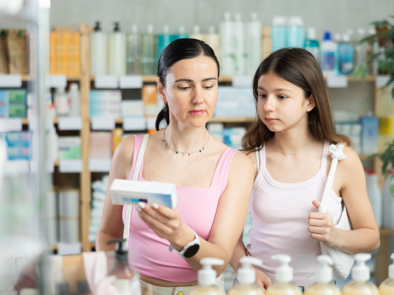 Madre e hija leyendo la composición de la medicina en la caja de la farmacia