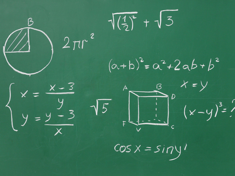 Figuras geométricas dibujadas y fórmulas matemáticas en pizarra verde.