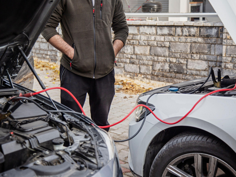 Hombre arrancando un coche con cables puente al aire libre