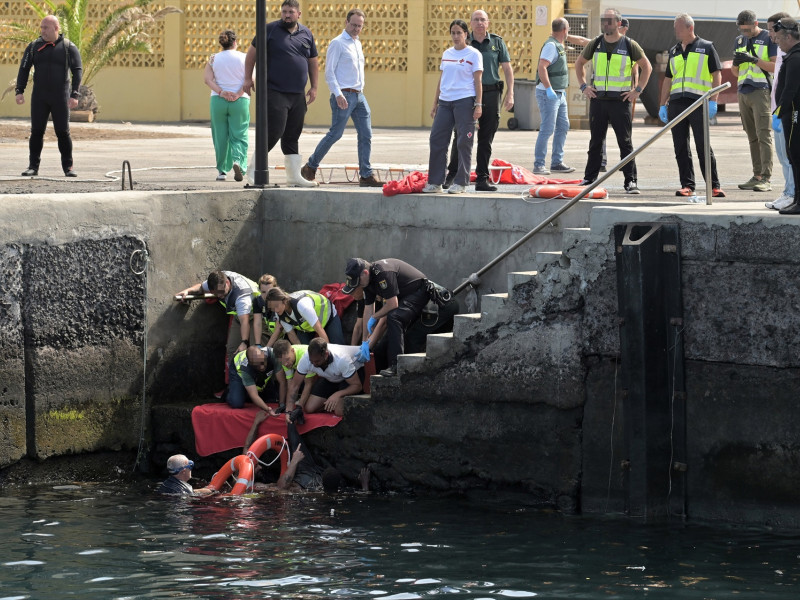 Agentes de Policía Nacional rescatan a uno de los migrantes que viajaba en el cayuco que ha volcado a su llegada al puerto de La Restinga