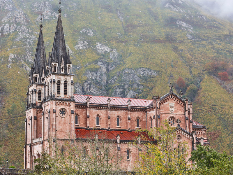 Pintoresca basílica de piedra roja y montañas en Covadonga