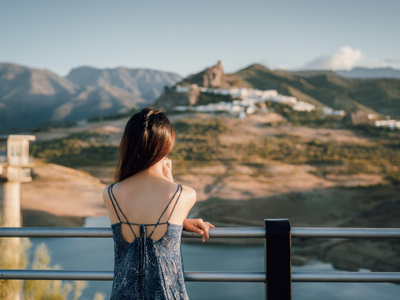 Mujer con vestido azul mirando el casco antiguo de Zahara de la Sierra en Cádiz