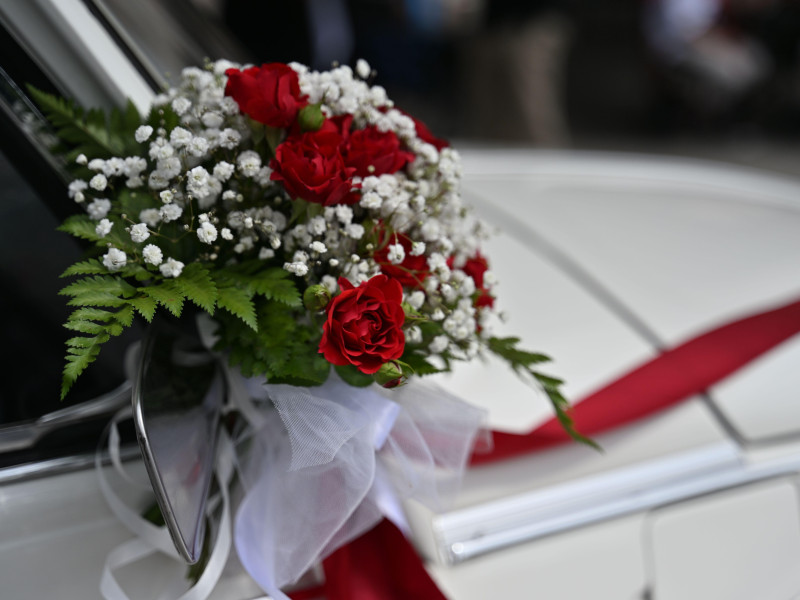 Primer plano de un ramo de novia atado al espejo retrovisor de un coche de lujo.