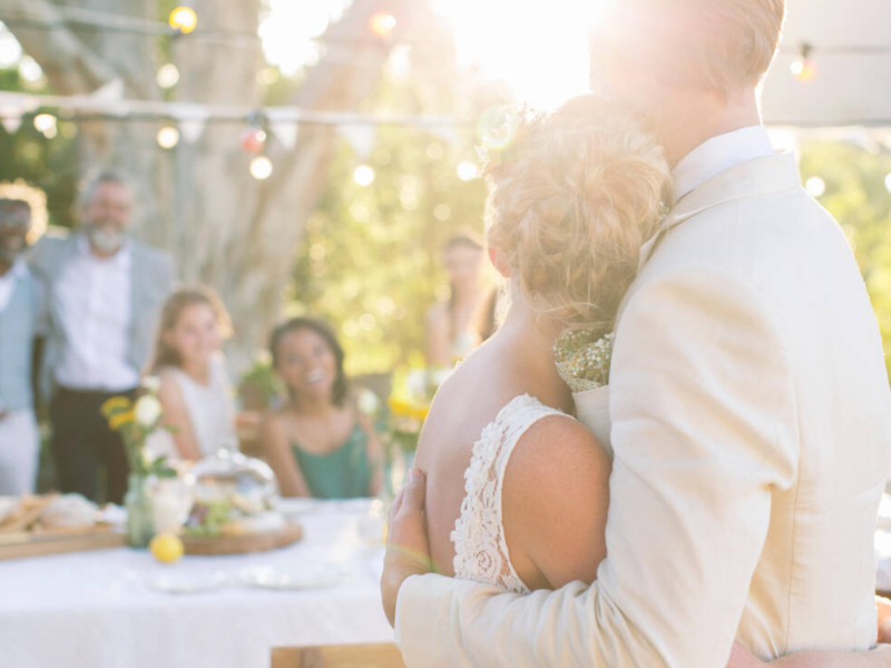 Dos novios se abrazan delante de sus familiares el día de su boda