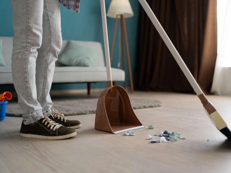Mujer barriendo el piso con escoba y recogedor haciendo limpieza de la casa en la sala de estar