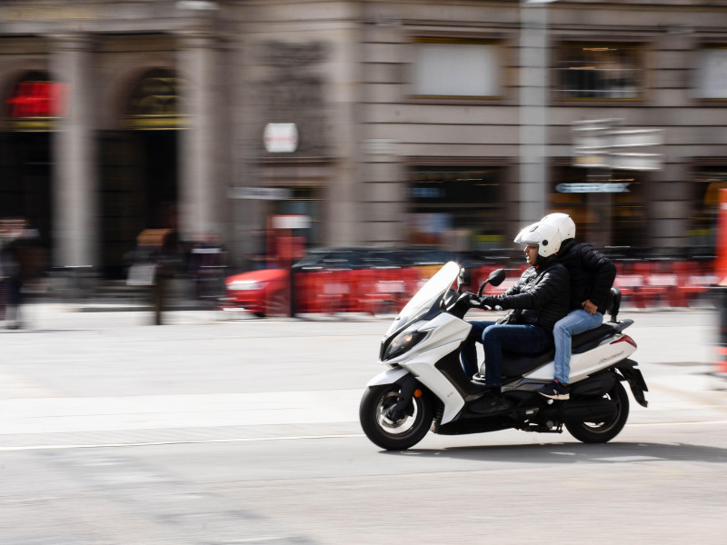 Conductor y un pasajero conduciendo un motor por las calles de Barcelona