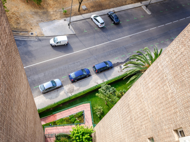 Vista de una calle residencial de la ciudad desde un edificio, con muchos estacionamientos vacíos un día de vacaciones