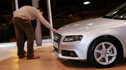 Una persona observando un nuevo modelo de Audi en el concesionario.