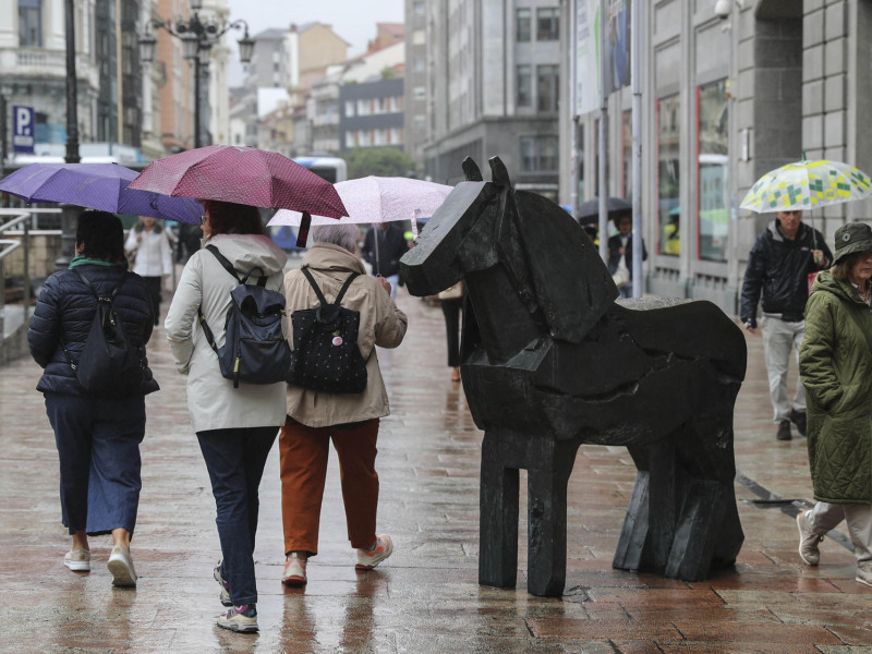 Un grupo de mujeres con paraguas junto a la escultura de Manolo Valdés, en la plaza de la Escandalera de Oviedo