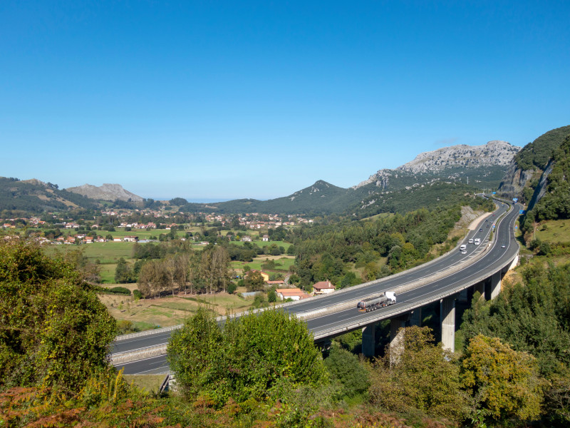 Carretera en medio de verdes montañas y viaducto de hormigón.