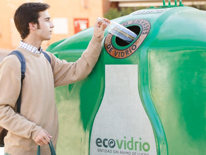Un joven deposita una botella en el contenedor del vidrio