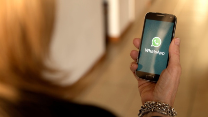 Una mujer sostiene su teléfono en la mano mientras abre la aplicación de WhatsApp