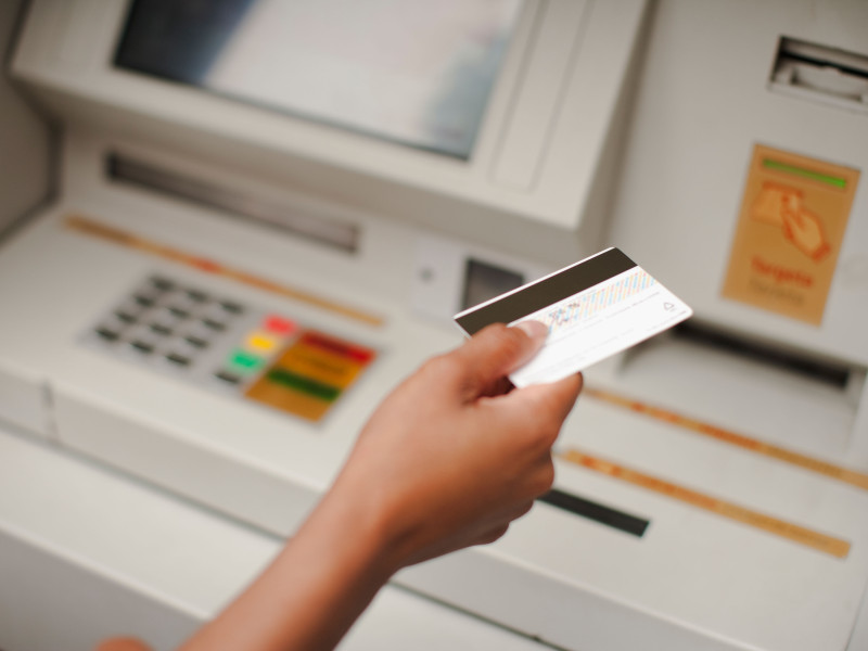 Una persona sostiene una tarjeta en el cajero del banco