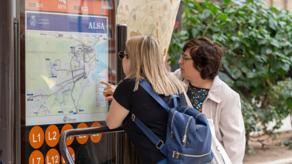 Dos personas consultan la información de las líneas de autobús