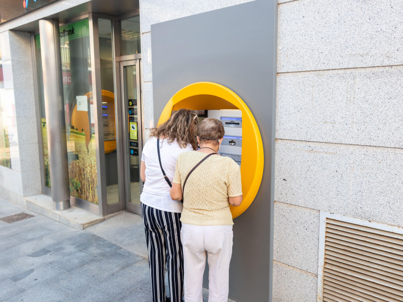 Mujeres usando tarjeta de crédito bancaria en un cajero automático en Huelva