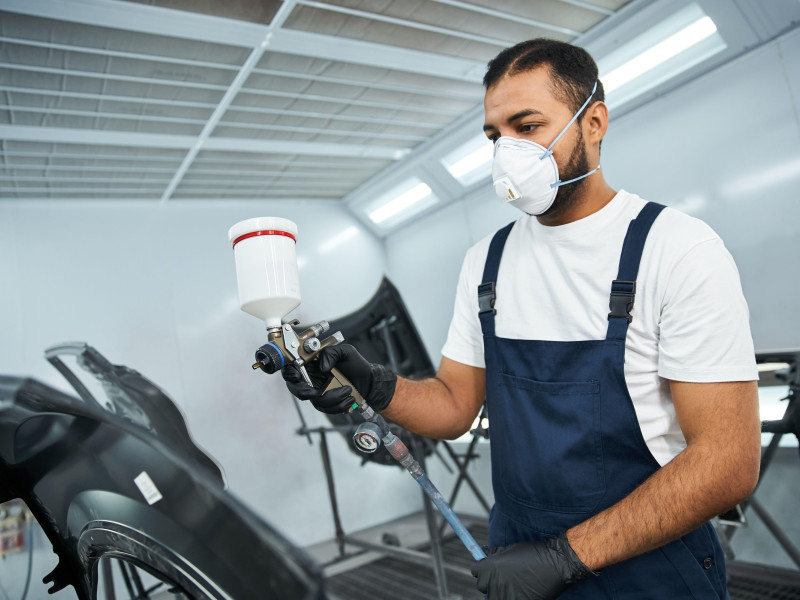 Un mecánico aplica pintura fresca a un componente del automóvil.