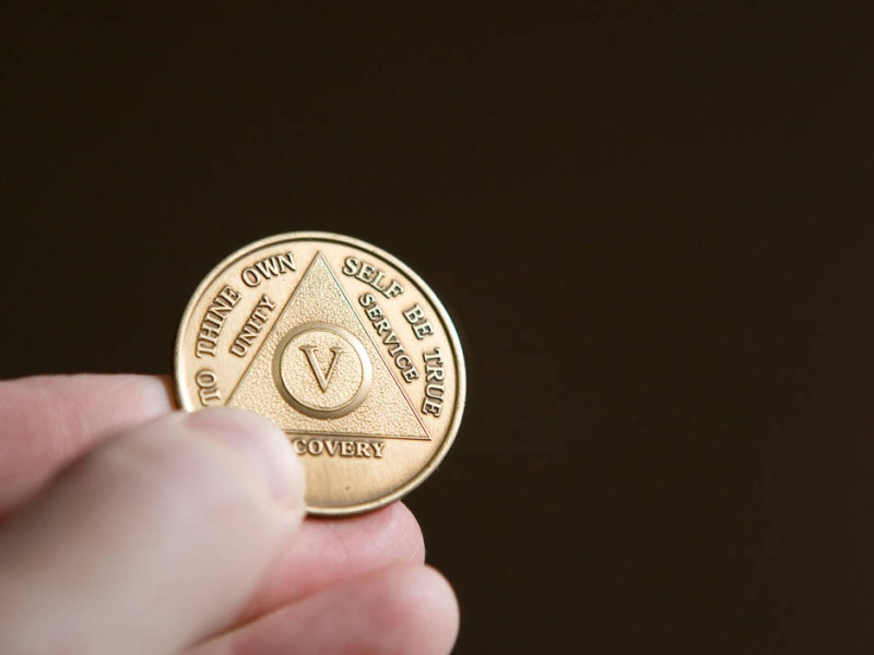 B8TDKM B8TDKM hand holding an Alcoholics Anonymous coin, or "chip" celebrating number of years sober