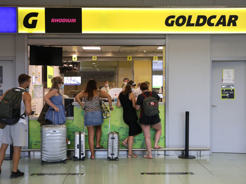 Los pasajeros esperan en los mostradores de alquiler de coches en el aeropuerto internacional de Ibiza.