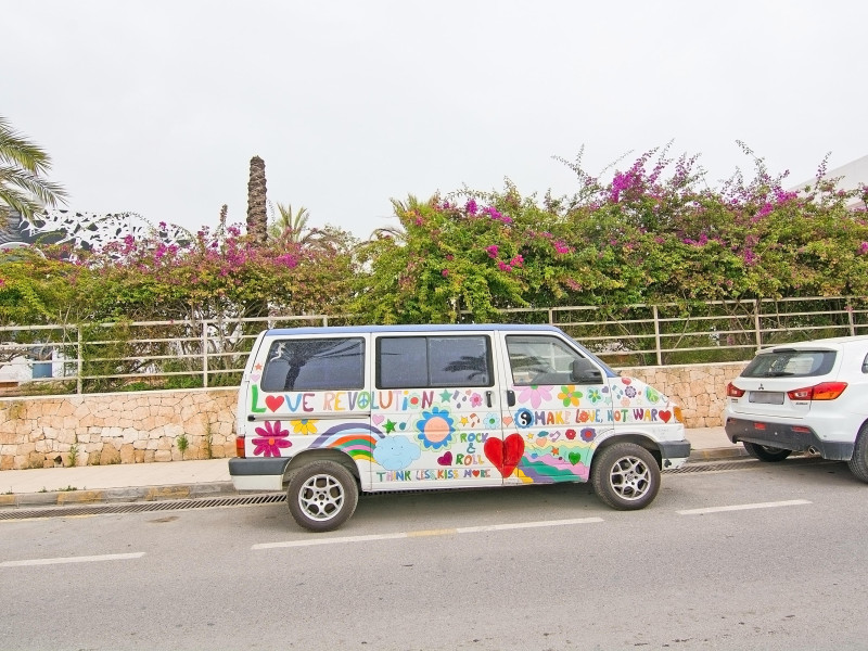 Coche hippie con mensaje de paz "Haz el amor y no la guerra" aparcado en una calle de Ibiza.