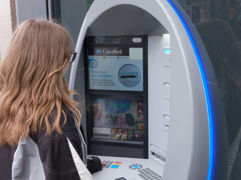 Una joven utiliza un cajero automático de CaixaBank en Madrid