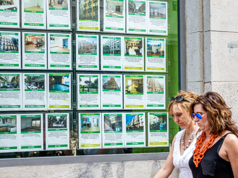 Personas pasan por delante de una inmobiliaria de Madrid