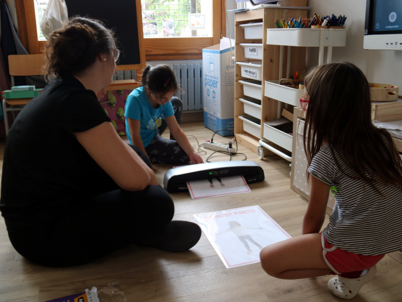 Dues alumnes de l'escola amb la seva professora utilitzant una petita impresora per fer una activitat.